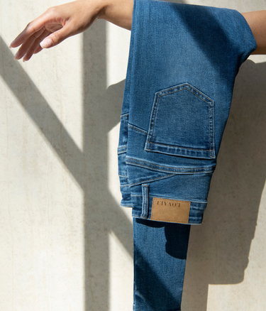 LOVALL Denim Jeans folded over a woman's arm.